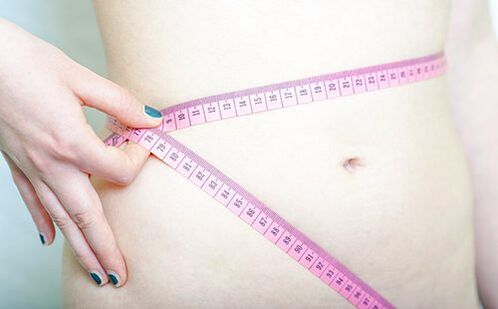 A girl measures her waist to record the results of following the Dukan diet